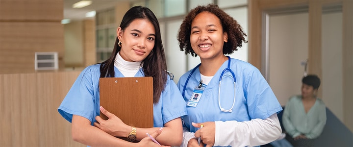 Two smiling medical professionals in blue scrubs